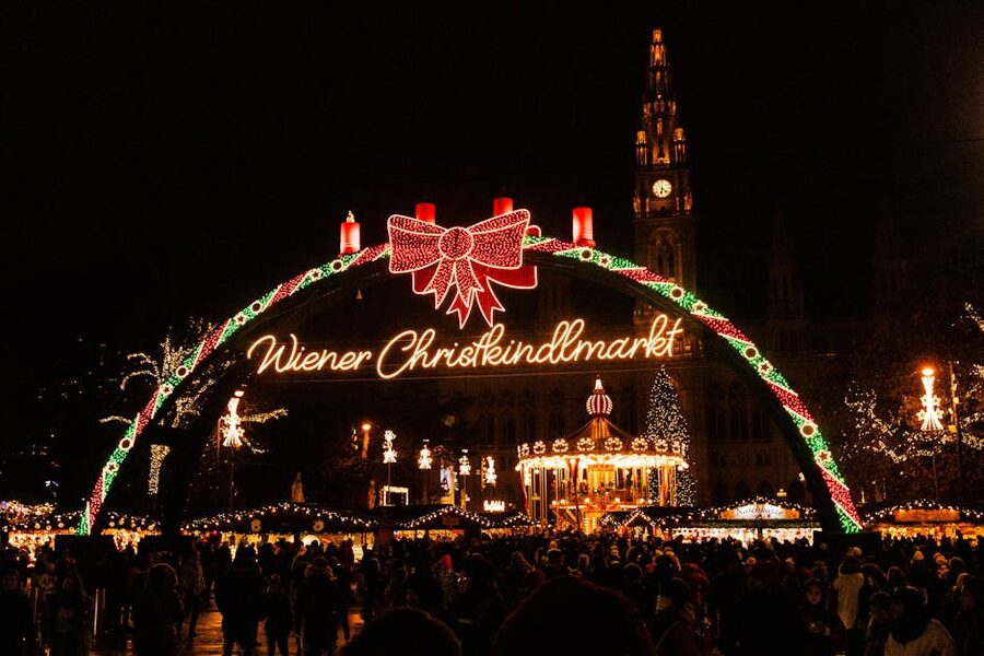 Lit entrance arch to Vienna Christkindlmarkt at Rathausplatz with festive crowds