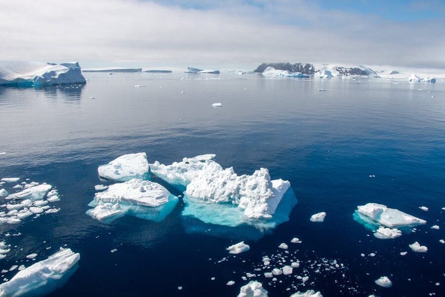 Tabular and weathered icebergs in clear Antarctic Peninsula waters under partly cloudy sky
