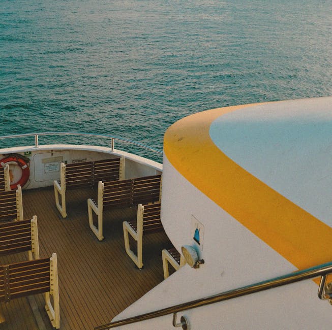 Empty cruise ship deck with wooden seats overlooking calm sea at sunset