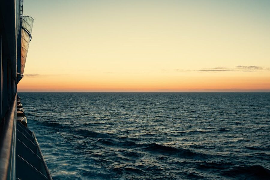 A wooden cruise ship deck looking out across the open sea at sunset