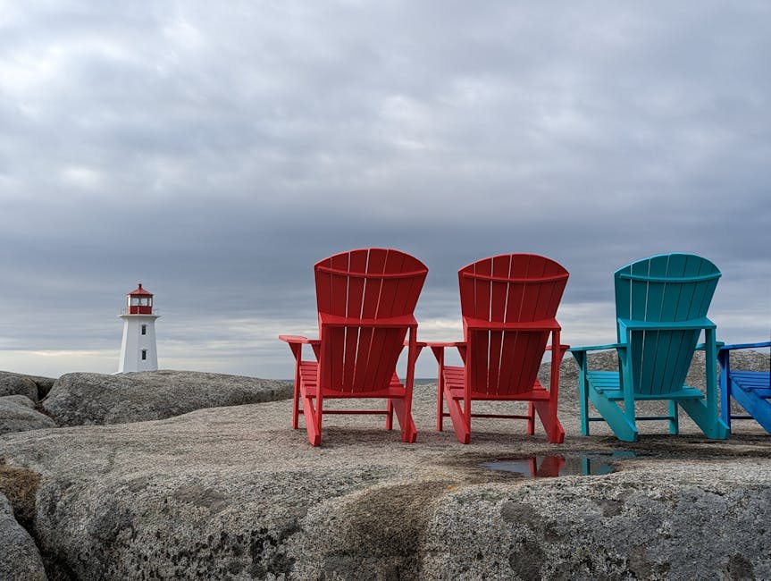 Red and blue Adirondack chairs facing Peggys Cove Lighthouse Nova Scotia