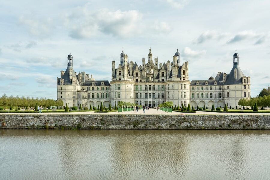 Chateau de Chambord reflected in calm water under a bright sky