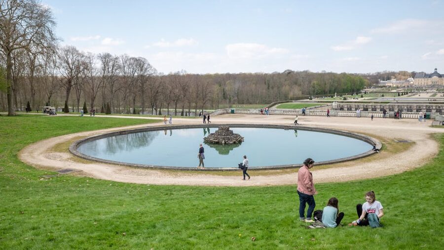 Visitors near the pond at Vaux-le-Vicomte on a sunny day