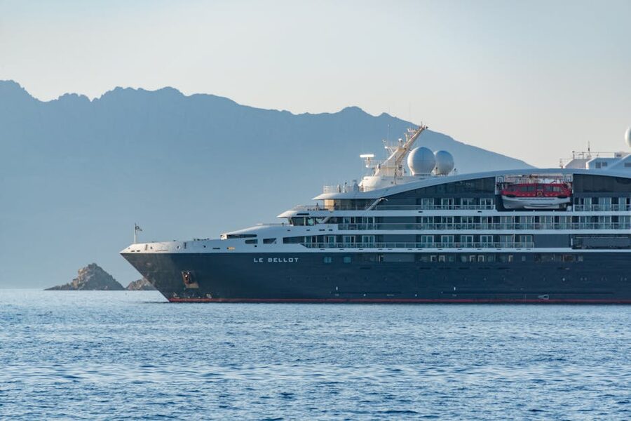Small expedition cruise ship sailing past mountains