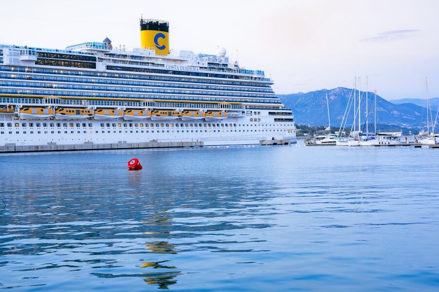 A small cruise ship docked alongside in Ajaccio, Corsica, with the town and mountains behind
