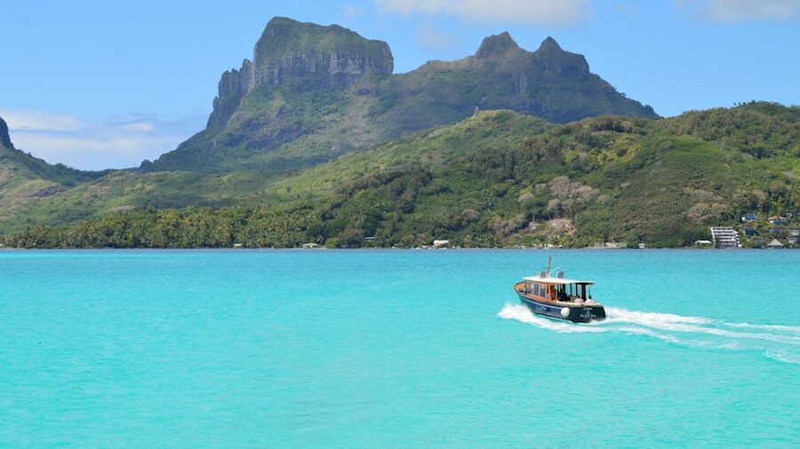 A boat on the turquoise water near the green peaks of Bora Bora, French Polynesia