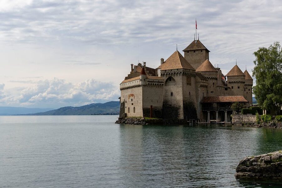 Chillon Castle on Lake Geneva with lush hills behind it