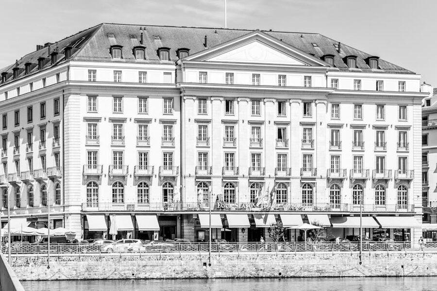 Historic grand hotel facade in Geneva reflected on lake waters
